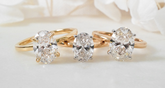 http://three%20oval%20diamond%20engagement%20rings%20on%20white%20surface%20in%20yellow%20gold