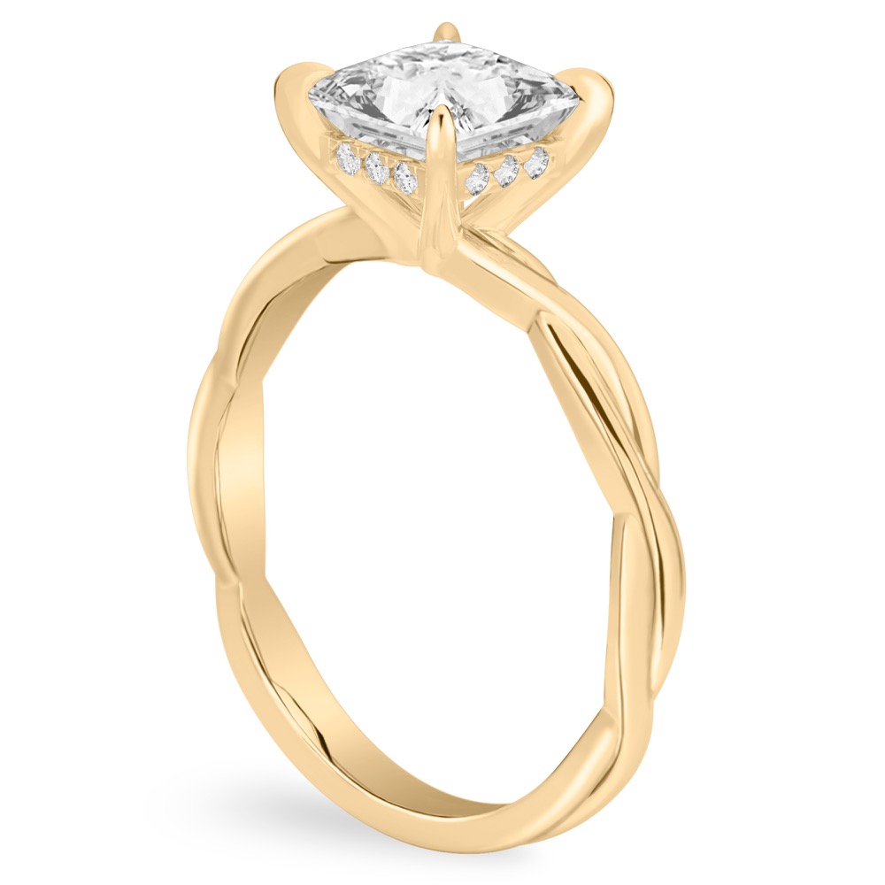 Angle view of princess cut diamond twisted hidden halo engagement ring in yellow gold